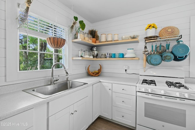 kitchen featuring white gas range oven, dark wood-style floors, white cabinetry, and a sink