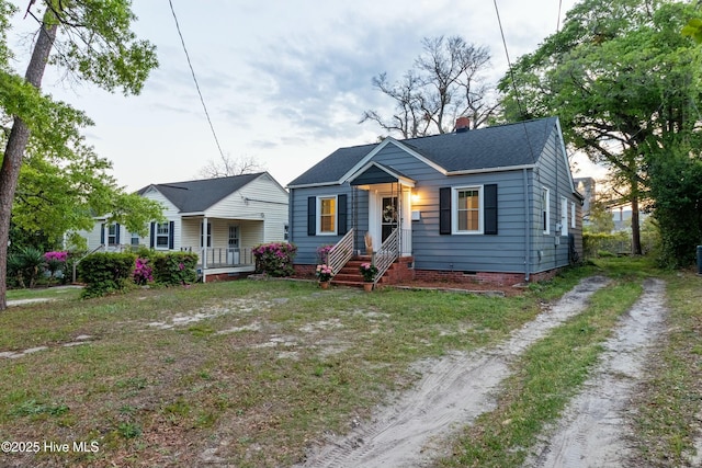 bungalow-style home with a chimney, a shingled roof, driveway, and crawl space