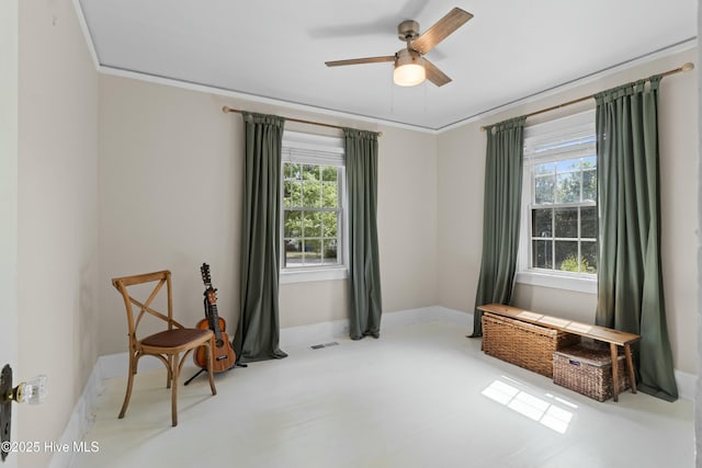 living area with a healthy amount of sunlight, a ceiling fan, and baseboards