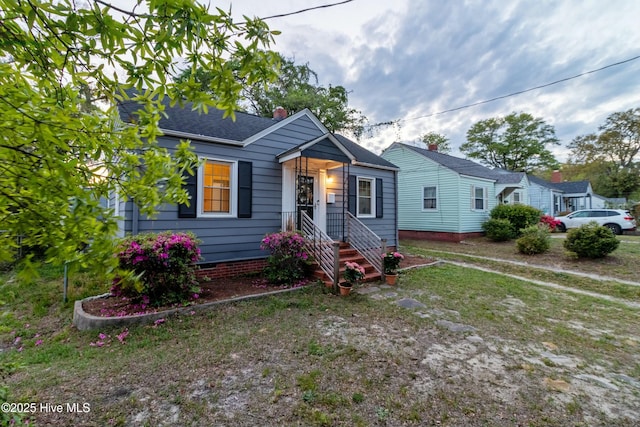 bungalow-style home with a chimney and roof with shingles