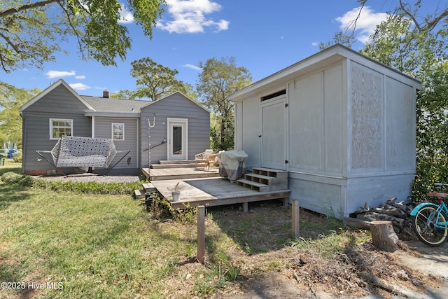 back of property featuring a deck, a yard, and entry steps