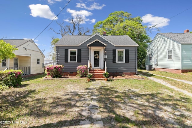 bungalow-style house with central AC, crawl space, a front lawn, and a shingled roof