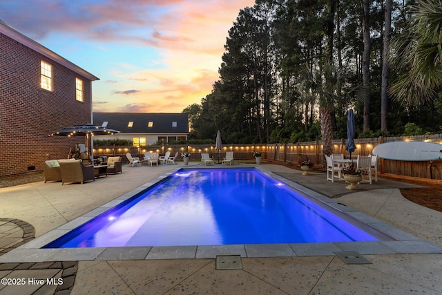 pool at dusk featuring an outdoor living space, a patio area, a fenced backyard, and outdoor dining space