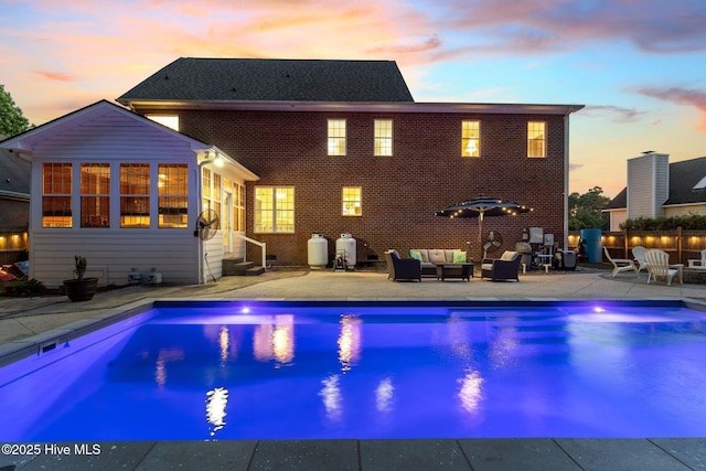 outdoor pool with an outdoor hangout area, entry steps, a patio area, and fence