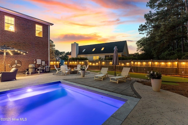 pool at dusk with a patio area, fence, and an outdoor fire pit