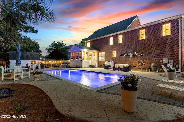 outdoor pool featuring an outdoor hangout area, a sunroom, a patio area, and an outdoor structure