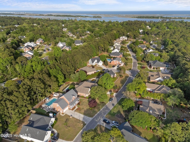 view of property location featuring nearby suburban area, a nearby body of water, and a heavily wooded area