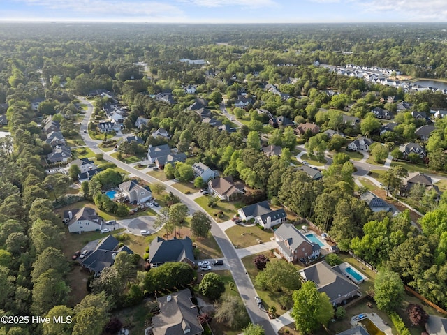 aerial view of property and surrounding area with a forest and nearby suburban area