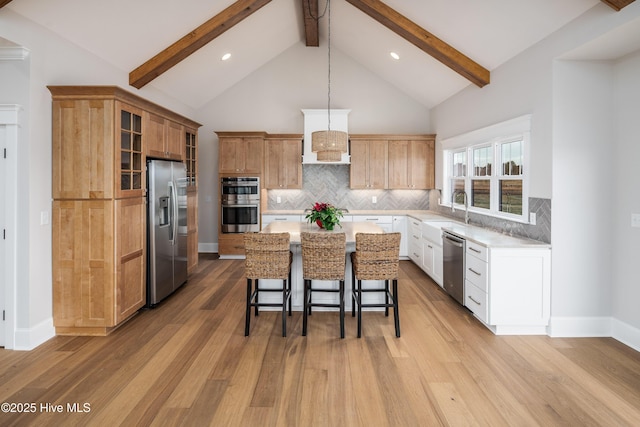 kitchen featuring a center island, a kitchen breakfast bar, a sink, tasteful backsplash, and appliances with stainless steel finishes