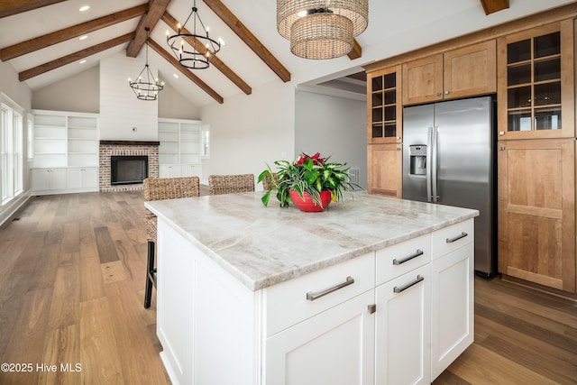kitchen featuring recessed lighting, light stone counters, wood finished floors, stainless steel refrigerator with ice dispenser, and a notable chandelier