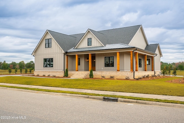 modern farmhouse style home featuring board and batten siding, covered porch, a front yard, metal roof, and a standing seam roof