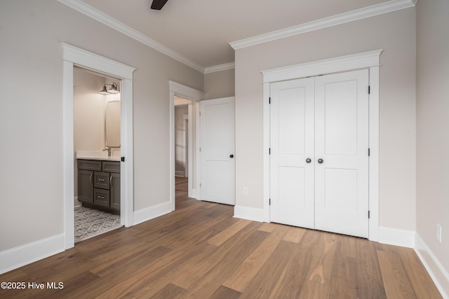 unfurnished bedroom featuring wood finished floors, a closet, baseboards, and ornamental molding