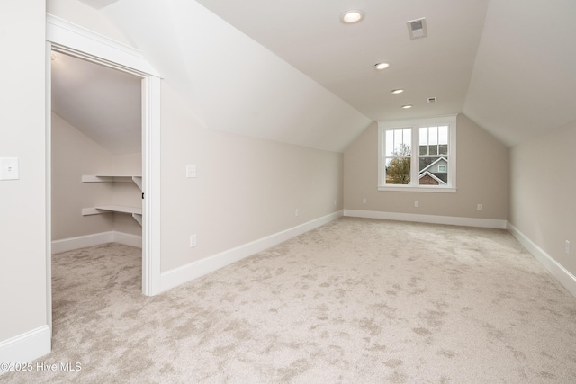 additional living space with baseboards, lofted ceiling, visible vents, and carpet floors