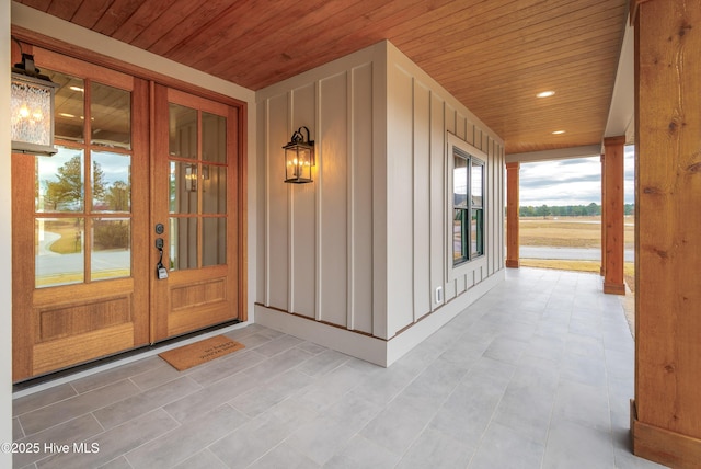 view of exterior entry with board and batten siding, french doors, and covered porch