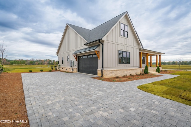 view of home's exterior featuring decorative driveway, board and batten siding, covered porch, metal roof, and a standing seam roof