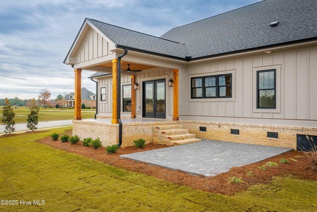 rear view of house featuring board and batten siding, crawl space, french doors, and roof with shingles