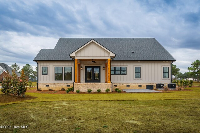 rear view of property with a yard, central air condition unit, board and batten siding, crawl space, and roof with shingles