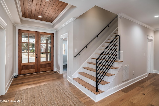 foyer entrance with wood finished floors, visible vents, ornamental molding, french doors, and stairs