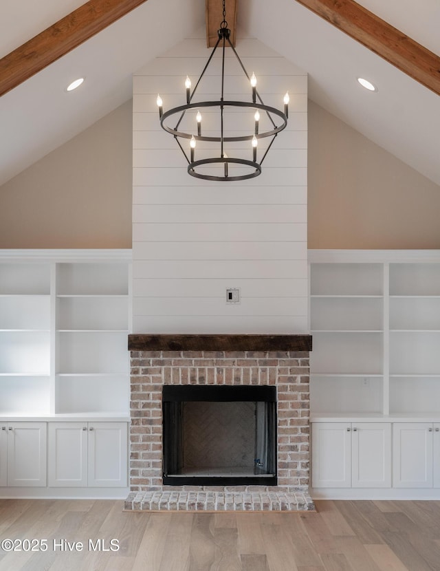 room details with a notable chandelier, a brick fireplace, wood finished floors, and beam ceiling