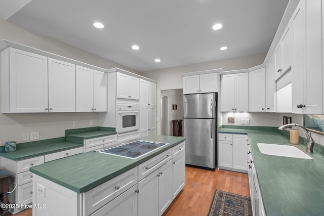 8 Driving Range Rd, Pinehurst, NC 28374 - kitchen featuring freestanding refrigerator, a sink, oven, black electric stovetop, and white cabinetry