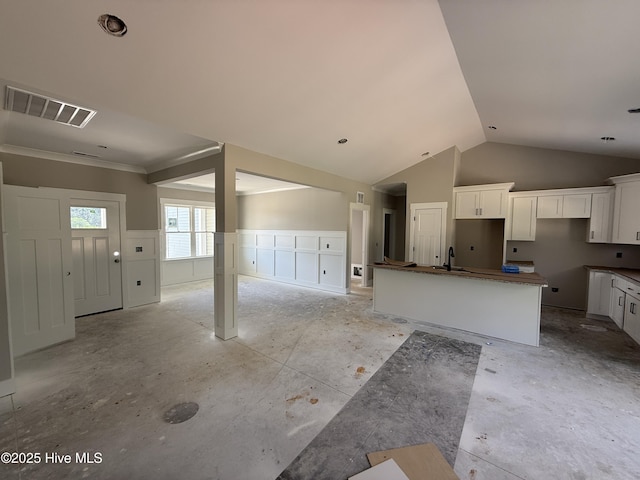 125 Tee Dr, Selma, NC 27576 - kitchen featuring white cabinetry, a kitchen island, wainscoting, open floor plan, and vaulted ceiling