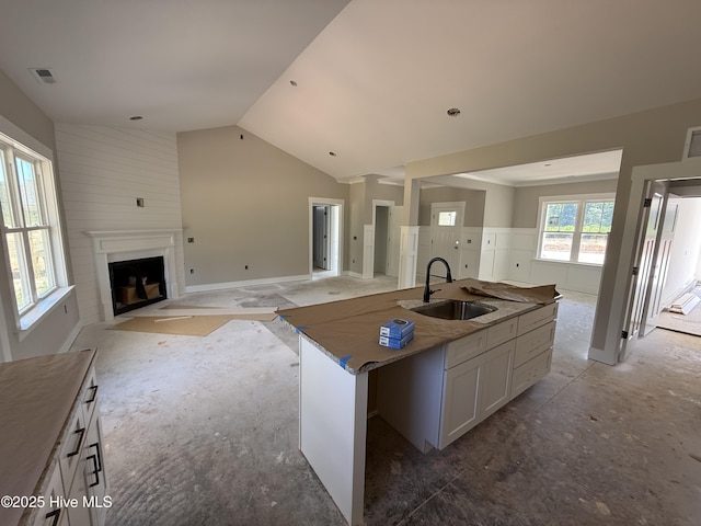125 Tee Dr, Selma, NC 27576 - kitchen featuring a fireplace with flush hearth, vaulted ceiling, white cabinetry, open floor plan, and an island with sink