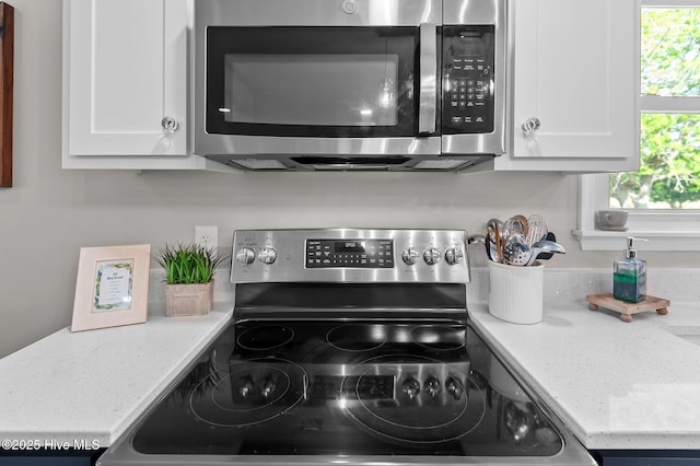 room details featuring white cabinets, appliances with stainless steel finishes, and light stone counters