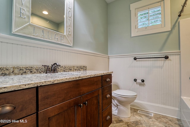 6445 Figure Eight Dr SW, Ocean Isle Beach, NC 28469 - bathroom with wainscoting, vanity, toilet, and a bathtub