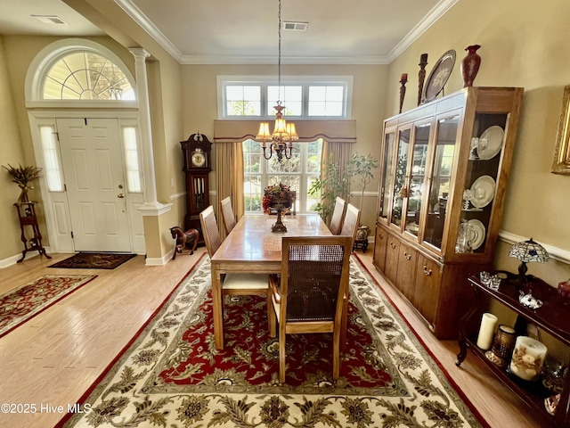 7473 Balmore Dr SW, Sunset Beach, NC 28468 - dining space featuring a chandelier, wood finished floors, ornamental molding, decorative columns, and a high ceiling