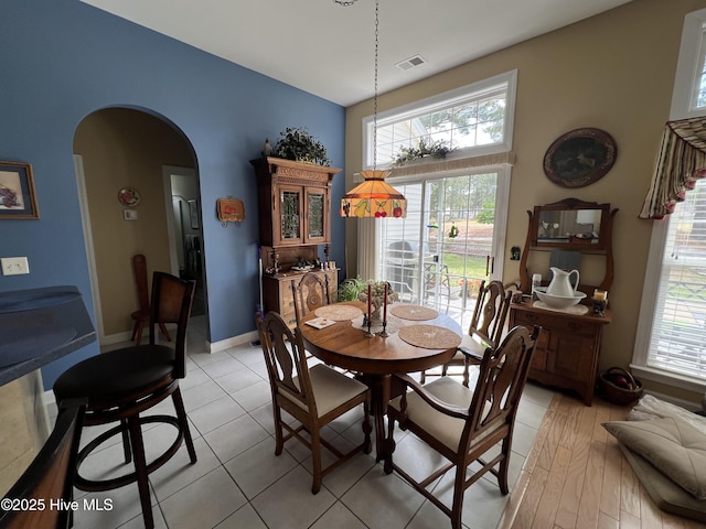 7473 Balmore Dr SW, Sunset Beach, NC 28468 - dining space featuring arched walkways, healthy amount of natural light, light tile patterned floors, and baseboards