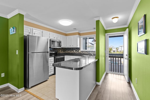 2714 W Beach Dr # 104, Oak Island, NC 28465 - kitchen featuring white cabinets, stainless steel appliances, a peninsula, and a sink