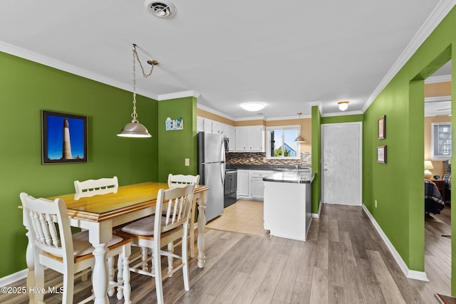 2714 W Beach Dr # 104, Oak Island, NC 28465 - kitchen with white cabinets, light wood finished floors, tasteful backsplash, visible vents, and freestanding refrigerator
