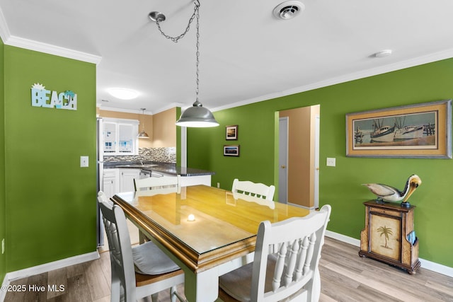 2714 W Beach Dr # 104, Oak Island, NC 28465 - dining area with light wood-type flooring, crown molding, and baseboards