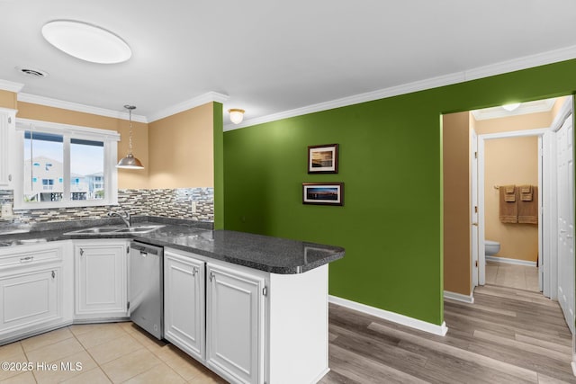 2714 W Beach Dr # 104, Oak Island, NC 28465 - kitchen with white cabinets, stainless steel dishwasher, ornamental molding, a sink, and a peninsula