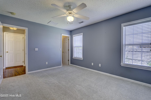 unfurnished room with a textured ceiling, visible vents, and carpet