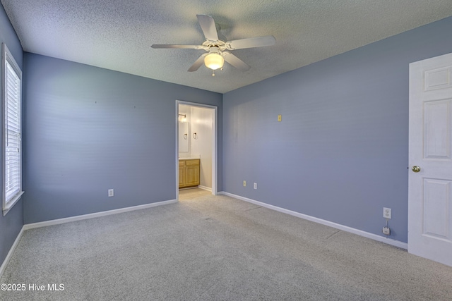 unfurnished bedroom featuring light colored carpet, a textured ceiling, and multiple windows