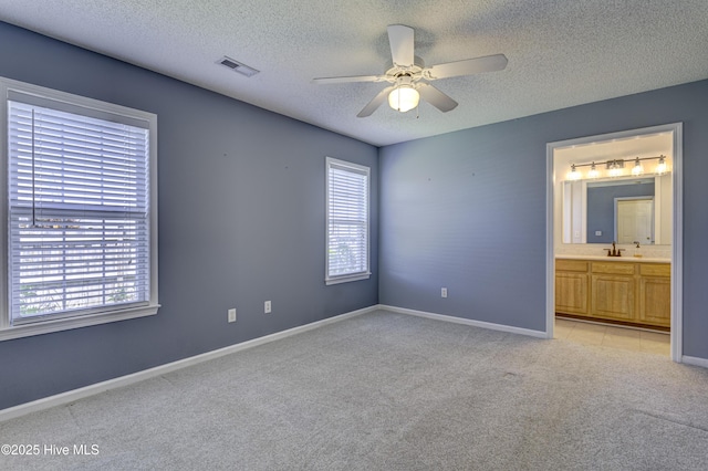 unfurnished bedroom featuring baseboards, light colored carpet, a textured ceiling, and visible vents