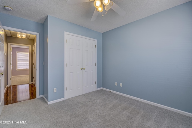 unfurnished bedroom featuring ceiling fan, a textured ceiling, baseboards, a closet, and carpet