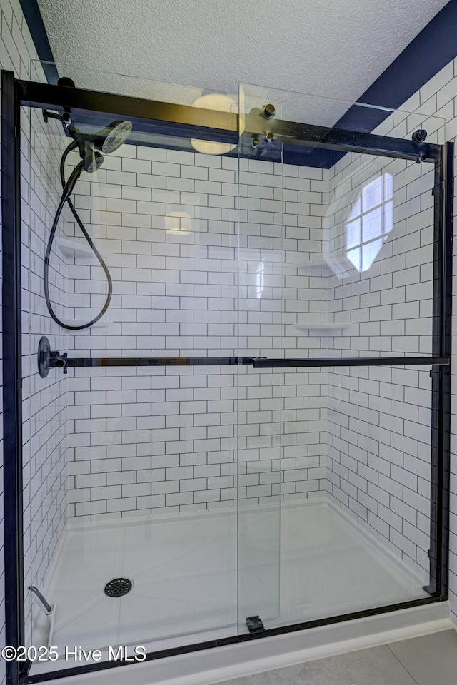full bathroom with a stall shower and a textured ceiling