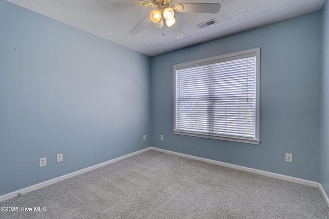 carpeted spare room with visible vents, a ceiling fan, a textured ceiling, and baseboards