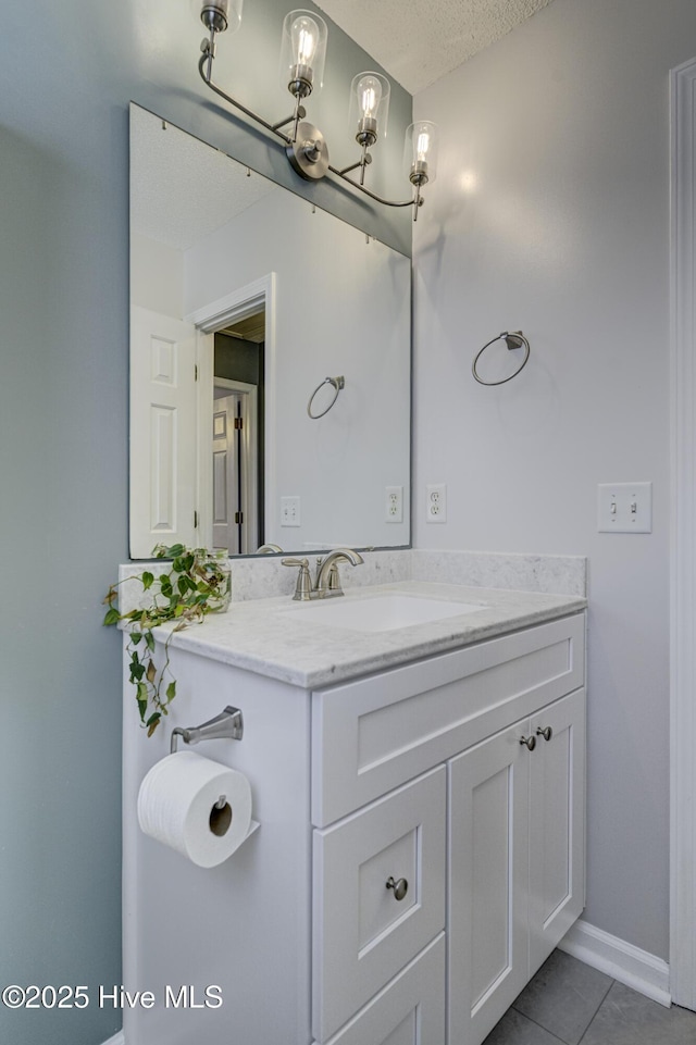 bathroom featuring tile patterned flooring, a textured ceiling, baseboards, and vanity