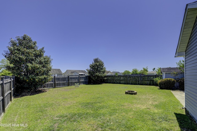 view of yard featuring a fenced backyard and a fire pit