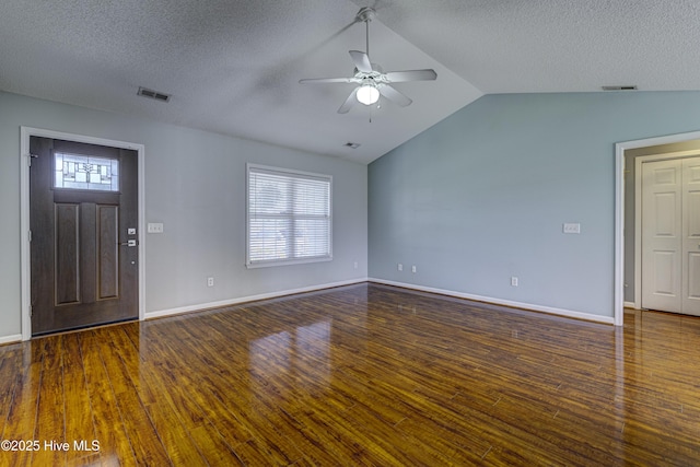 interior space with a ceiling fan, a textured ceiling, visible vents, vaulted ceiling, and wood finished floors