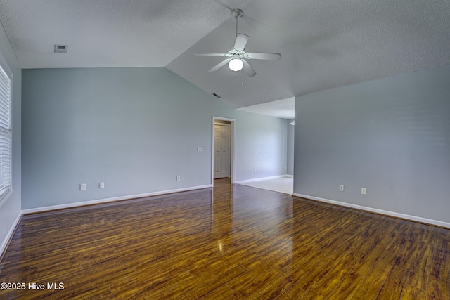 spare room with ceiling fan, visible vents, baseboards, wood finished floors, and vaulted ceiling