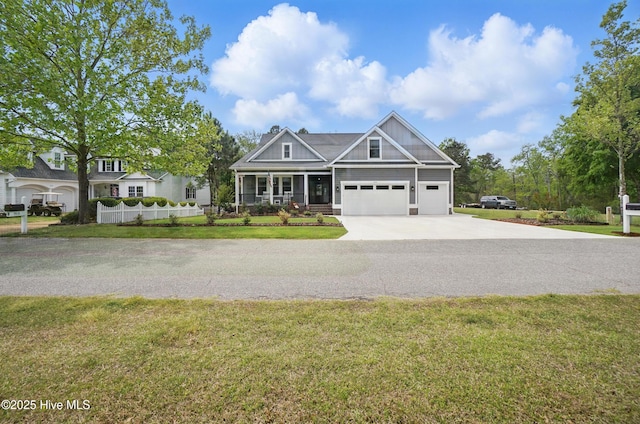 craftsman-style home with covered porch, a chimney, driveway, and a front lawn