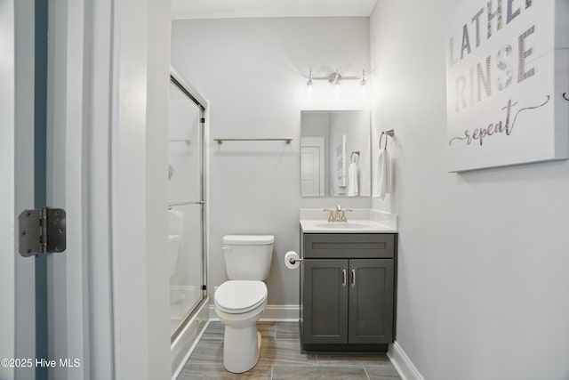 full bathroom featuring vanity, wood finished floors, toilet, baseboards, and a stall shower