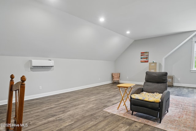 sitting room featuring lofted ceiling, wood finished floors, baseboards, an AC wall unit, and recessed lighting