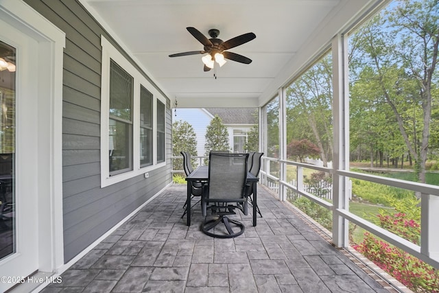 sunroom / solarium with outdoor dining area and a ceiling fan