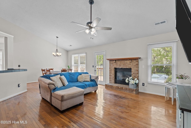 living area featuring visible vents, wood-type flooring, ceiling fan with notable chandelier, and lofted ceiling
