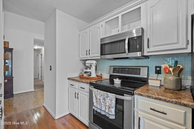 kitchen featuring baseboards, light wood-style flooring, tasteful backsplash, and stainless steel appliances